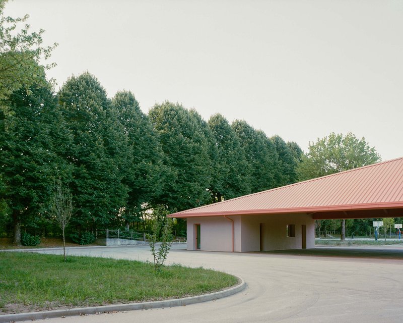 Covered portico with recessed openings and overhanging pink metal roof edge at dusk