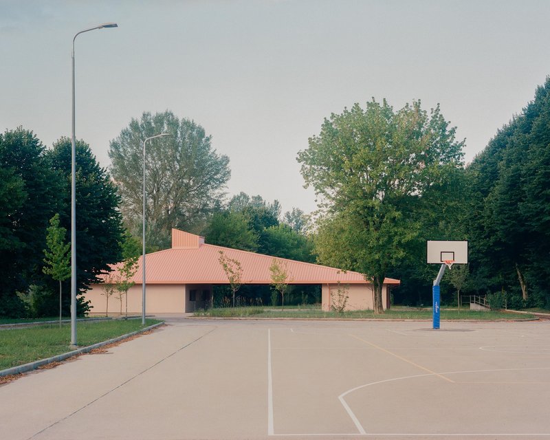 View from the adjacent basketball court showing the low-slung roof volume and street lamp
