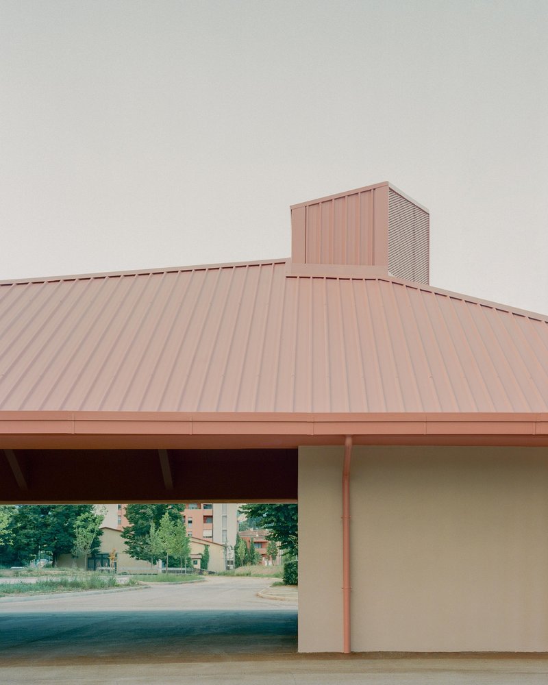 Corner view of the standing seam metal roof and perforated metal chimney under overcast sky