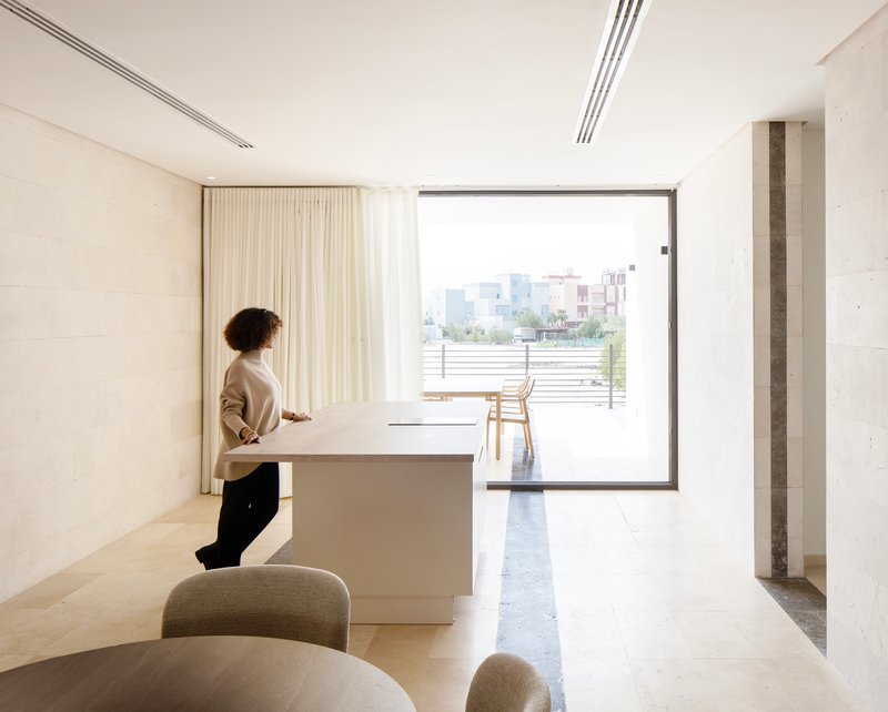 Living space with person standing at white counter facing sliding glass door to terrace beyond