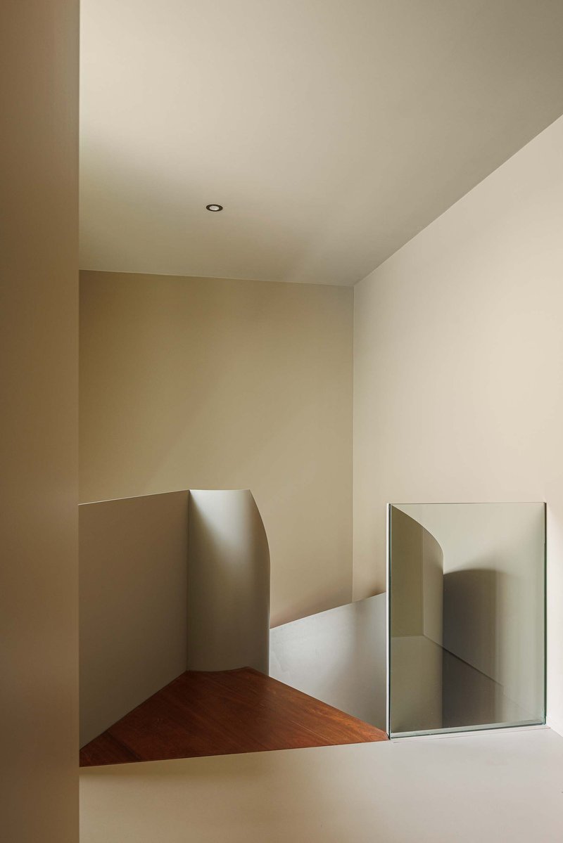 Upper-level corridor with angled walls, timber flooring, and rectangular mirror reflecting adjacent passageway