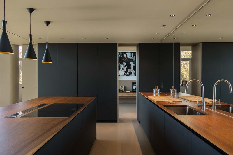 Kitchen with dual timber-topped islands, black cabinetry, and conical pendant lights overhead