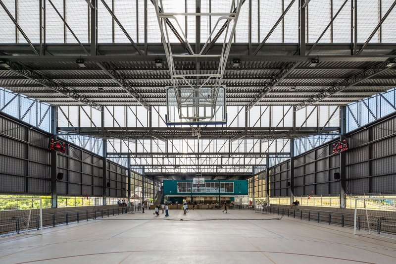 Full-height steel truss structure framing a large covered court with concrete floor