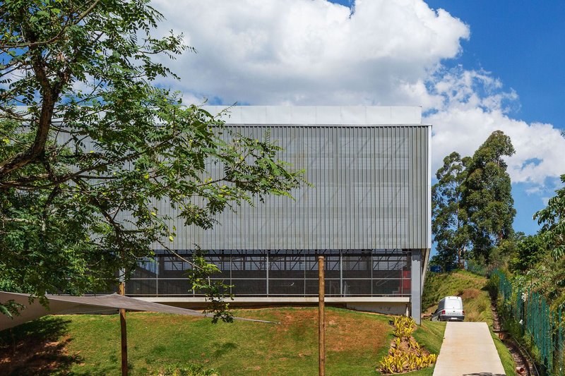 Two-story facade with vertical metal cladding and horizontal glazed strip on a sloped site