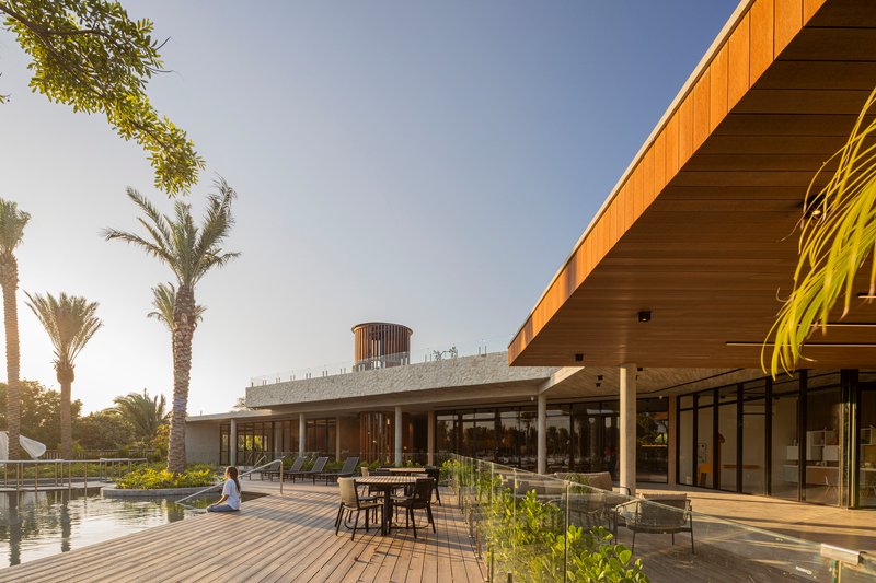 Timber-clad roof overhang and concrete terrace with pool and outdoor furniture at sunset