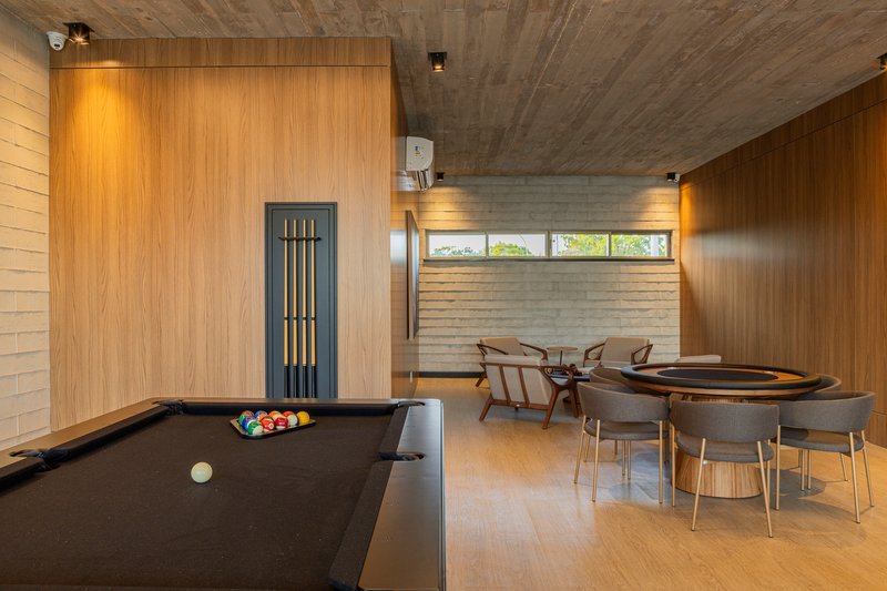 Recreation room with pool table and card table beneath exposed concrete ceilings and horizontal windows