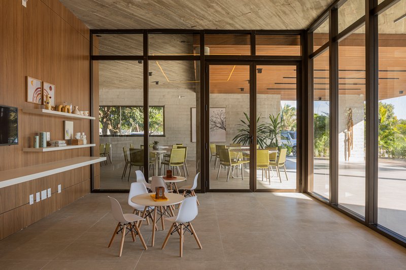 Interior dining area with steel-framed glass doors opening to poolside terrace with palm trees beyond
