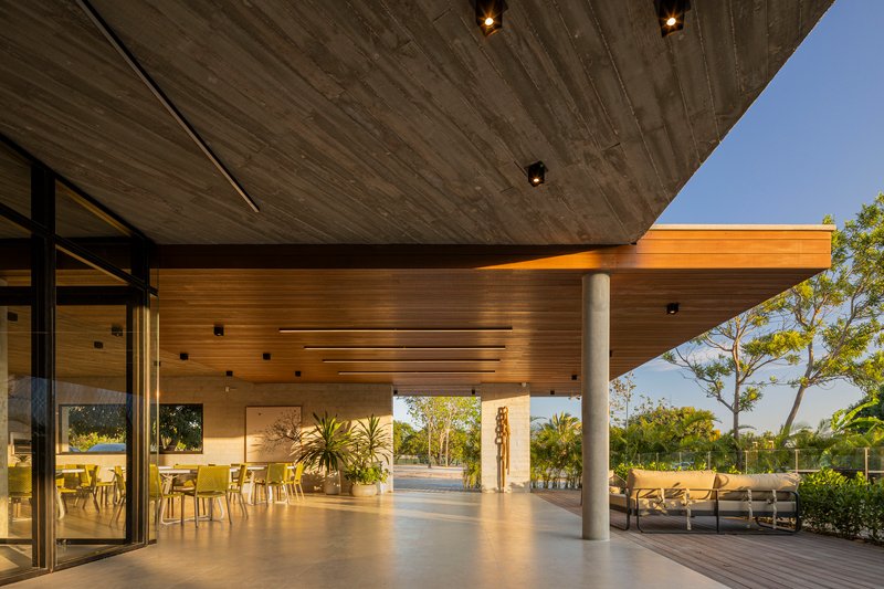 Covered terrace at dusk with board-formed concrete and timber ceilings supported by concrete columns