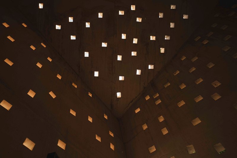 Upward interior view of scattered square openings puncturing the concrete ceiling plane