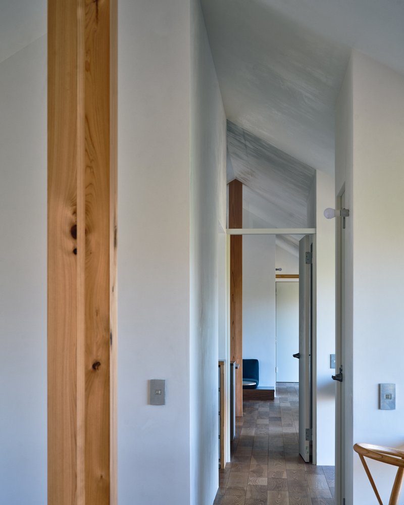 Hallway with exposed timber post beside doorways leading through white-walled rooms with vaulted ceilings