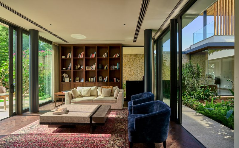 Living area with timber bookshelf wall and sliding glass doors opening to planted courtyard