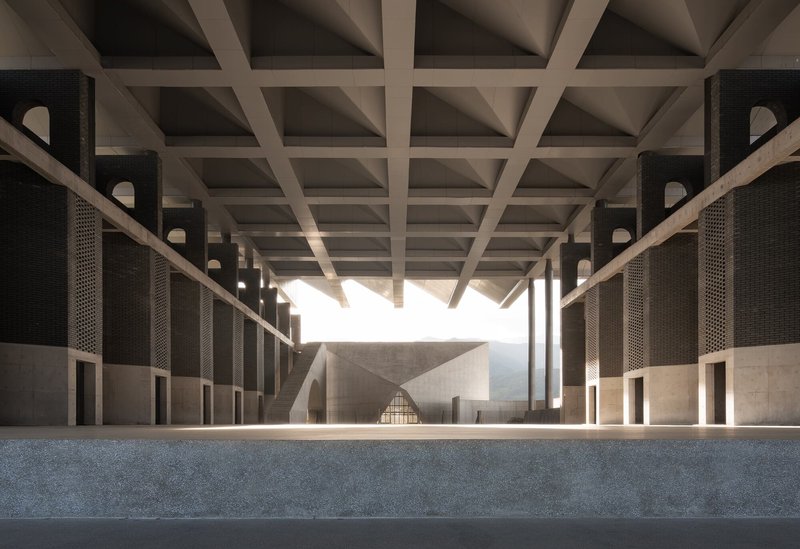Interior colonnade with coffered ceiling and perforated brick screens filtering natural light into the corridor