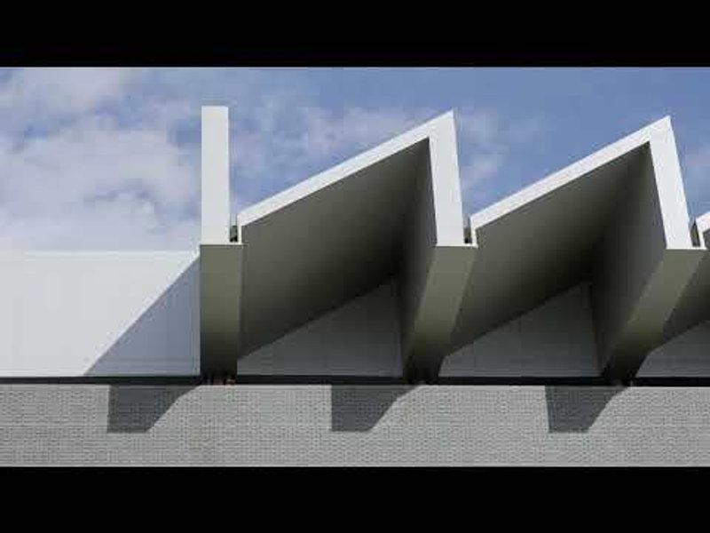 Close view of three sawtooth concrete roof elements against a cloudy sky