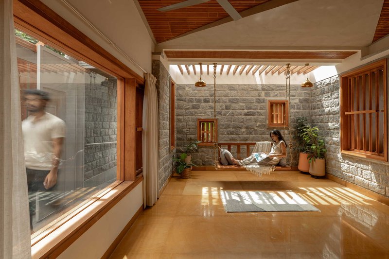 Interior courtyard with stone block walls, timber louvered ceiling and a person reading on the raised platform