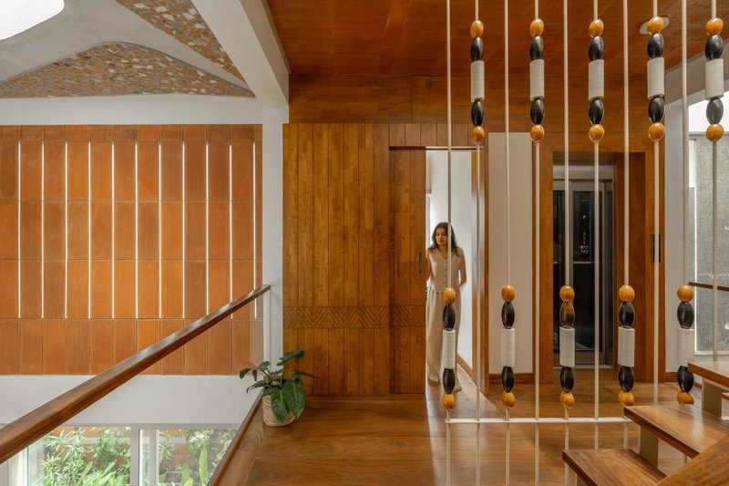 Upper landing with vertical timber screens and hanging bead divider as a person moves through the doorway