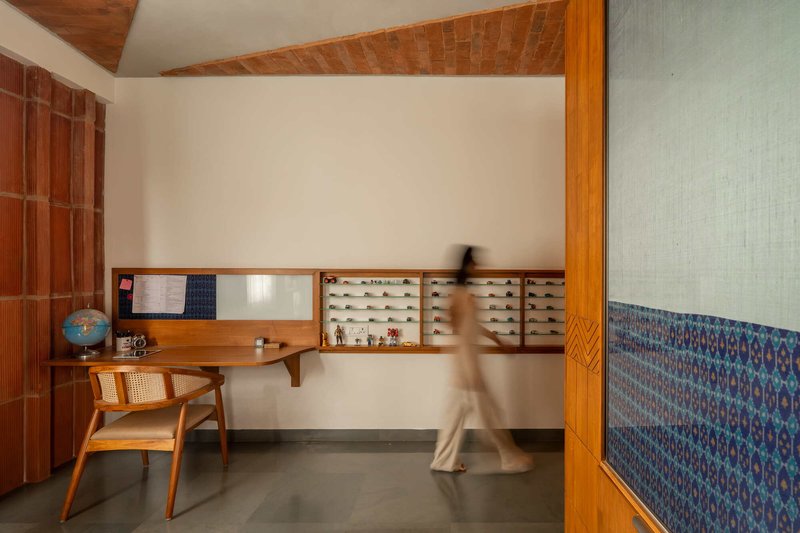 Study alcove with floating timber desk and display shelves as a person walks through