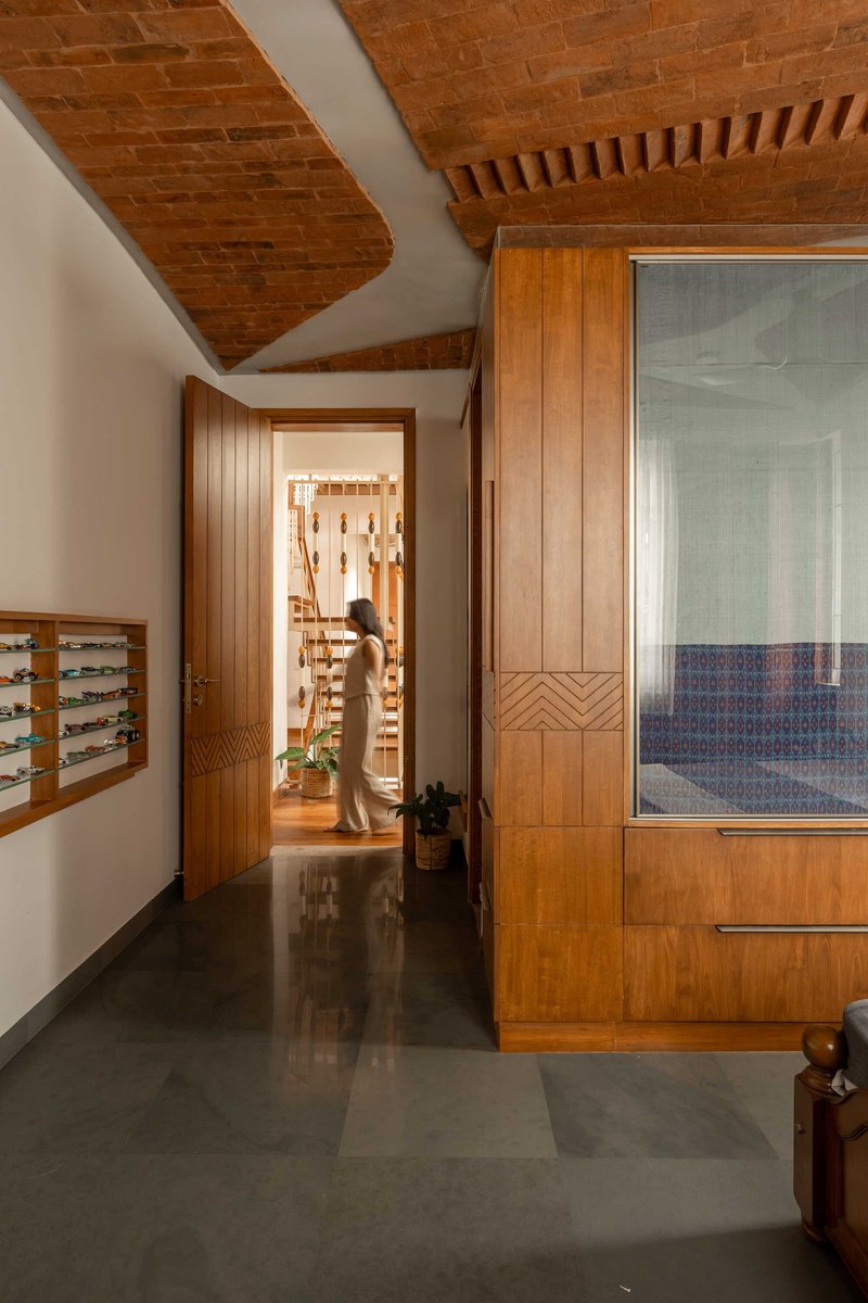 Corridor with vaulted brick ceiling and chevron-patterned timber door panels leading to interior rooms