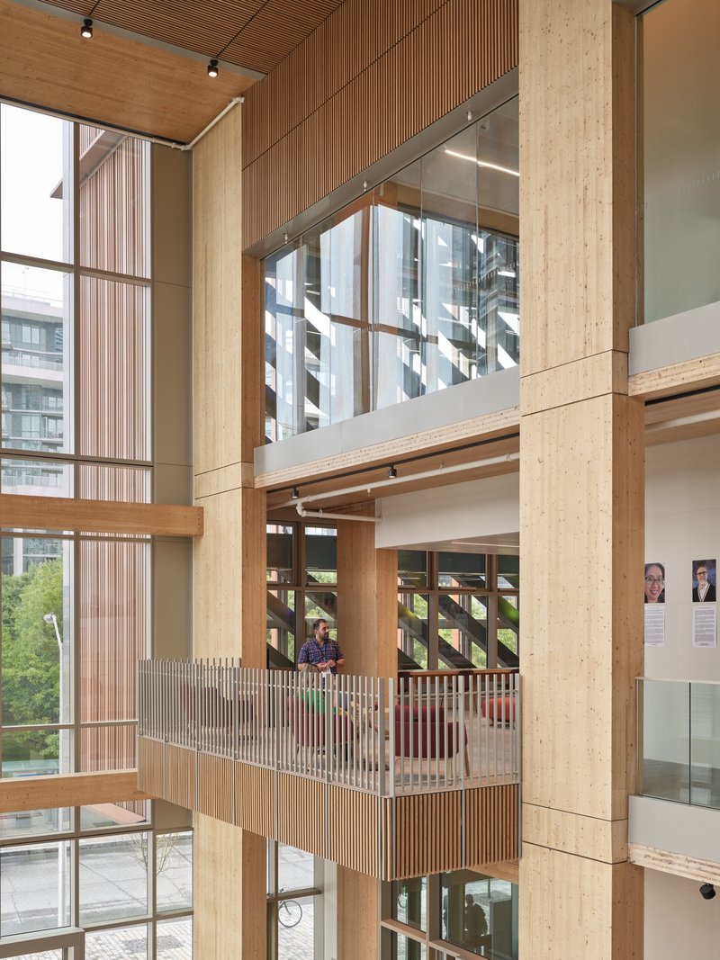 Multi-level interior showing timber balconies with vertical wood slat railings and exposed ceiling beams