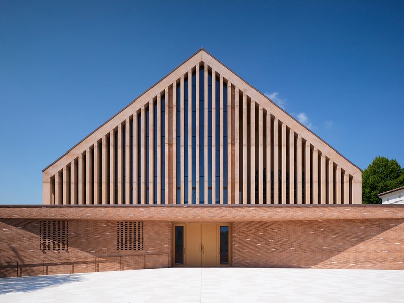 Front elevation showing vertical timber screens framing the entrance doors in a brick facade