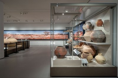 This image showcases an interior view of a museum exhibit, featuring a collection of ancient pottery