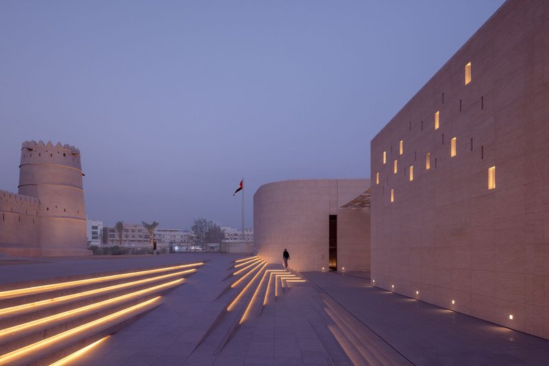 Illuminated stone staircase with integrated linear lighting leading to an entrance at dusk