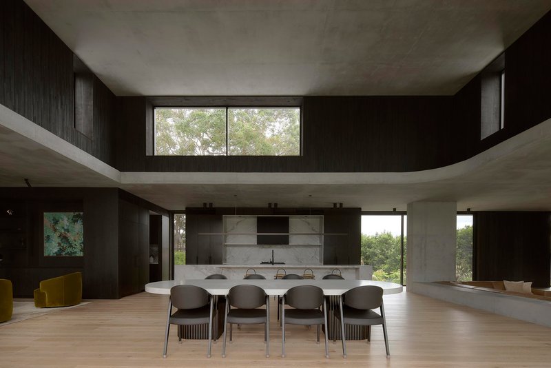 Double-height dining space with concrete mezzanine, black timber walls and clerestory windows
