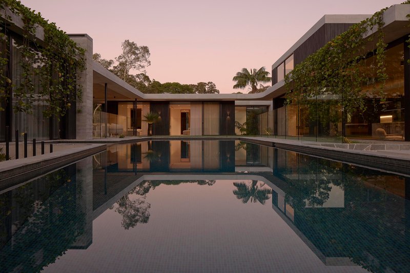 Courtyard pool reflecting glass pavilions and greenery at twilight