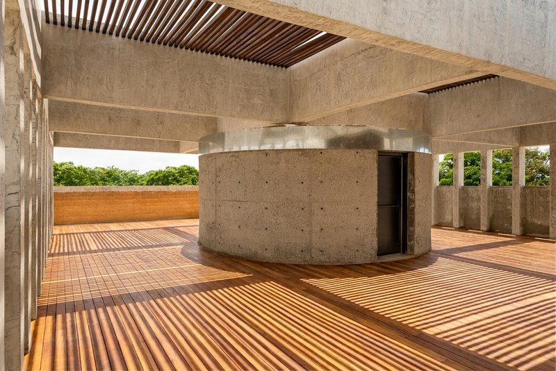 Rooftop terrace with timber slat flooring, slatted ceiling, curved concrete core, and view to greenery