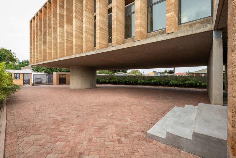 View across the brick courtyard showing the concrete slab hovering above on cylindrical supports
