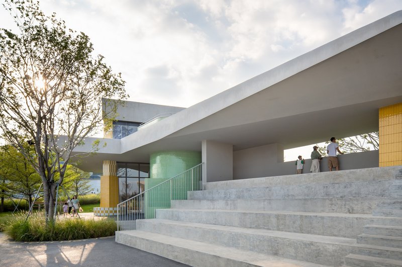 Wide concrete staircase ascending beneath a cantilevered soffit with visitors gathered above