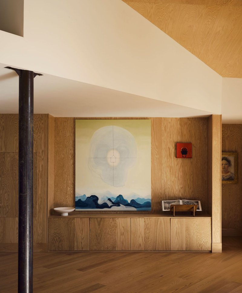 Oak credenza below a large artwork flanked by a slender black steel column in natural light