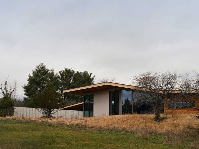 Exterior view of the low-pitched roof and white stucco walls surrounded by dormant grasses in winter