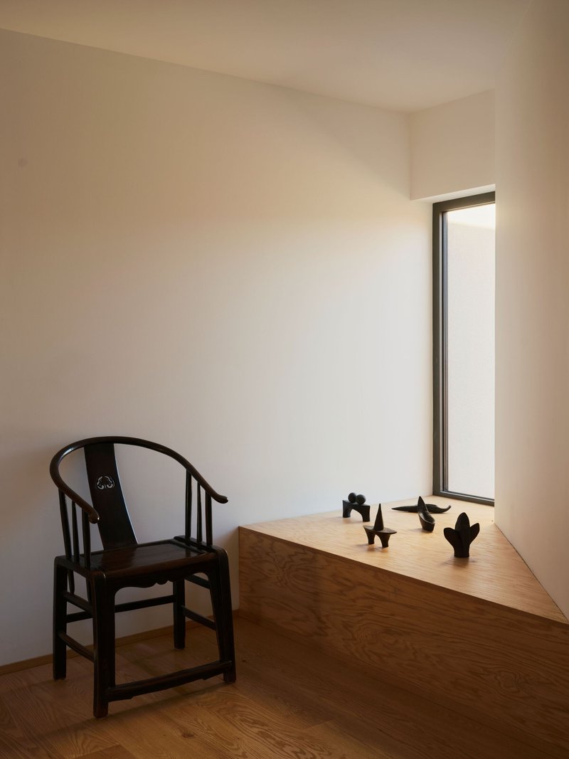 Built-in desk beside a tall narrow window with small sculptures arranged on the wood surface