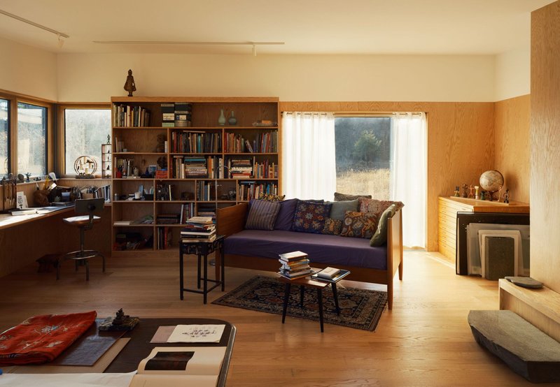 Library wall with integrated shelving adjacent to a daybed under a wide curtained window