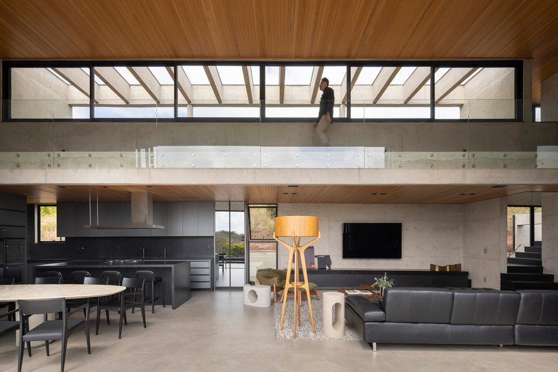 Open living area with mezzanine bridge and clerestory glazing above concrete walls