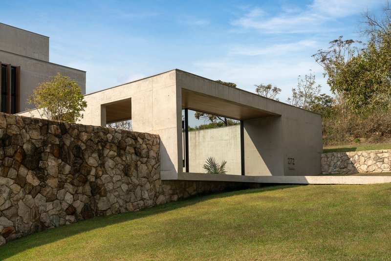 Street view of the concrete entry portal with stone gabion wall and lawn in afternoon light