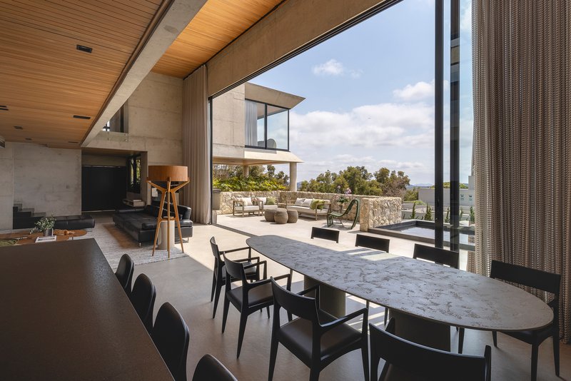 Dining area with marble table extending toward the outdoor terrace and pool