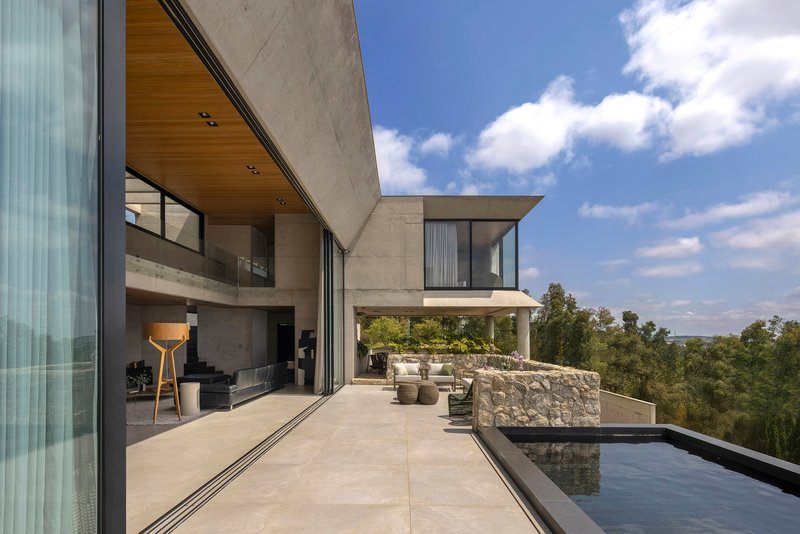 Terrace with stone wall, reflecting pool, and cantilevered volumes under blue sky