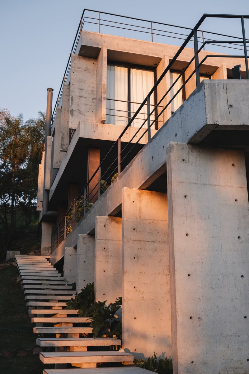 Exterior concrete staircase with open timber treads and steel railings illuminated by sunset glow