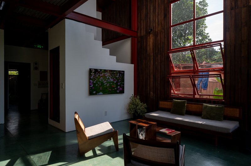 Double-height living room with red steel window frames and green polished concrete floor in afternoon light