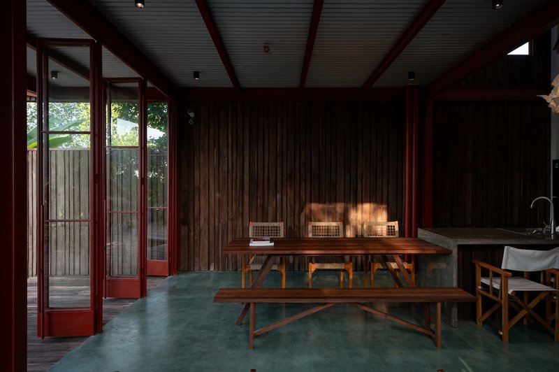 Dining area with timber table and benches on green polished concrete floor under corrugated ceiling