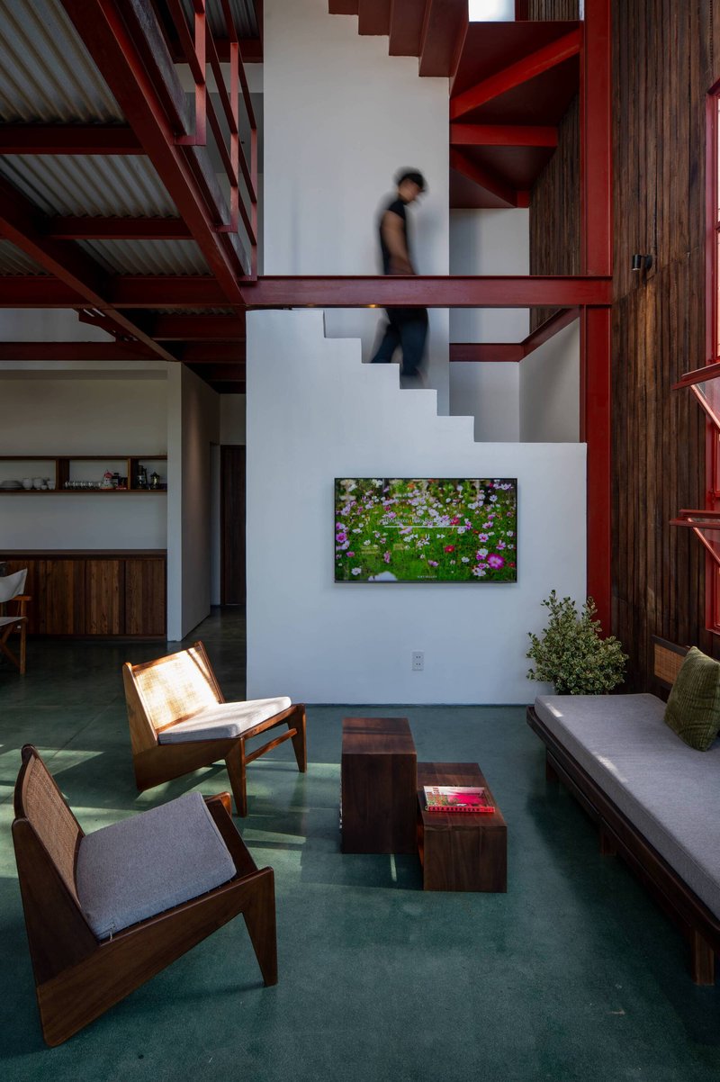 Interior double-height living space with red steel staircase and a person ascending in motion blur