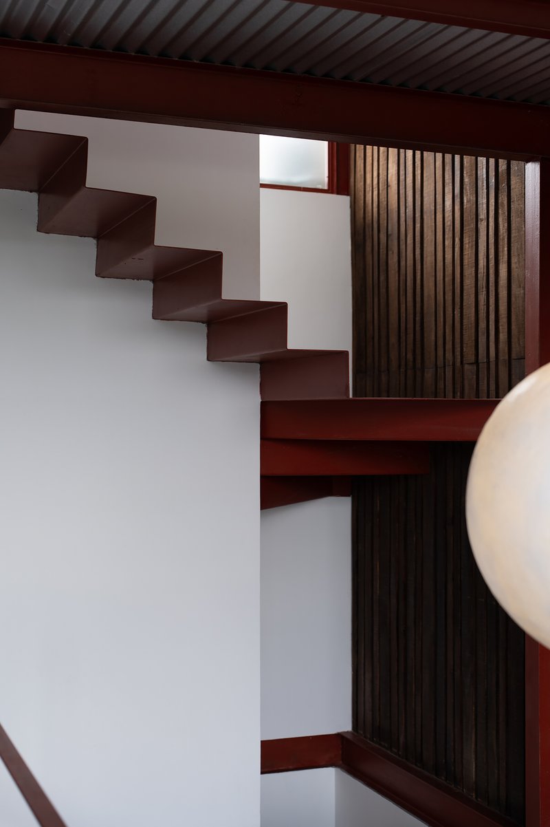 Upward view of the cantilevered staircase with vertical timber slat screen and corrugated ceiling