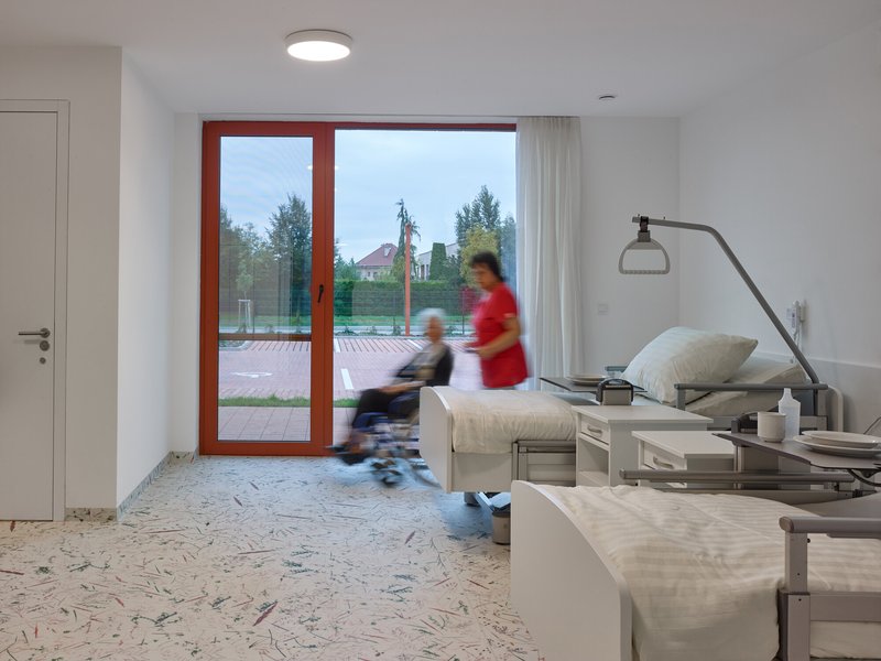 Interior corridor with terrazzo flooring and blurred figures passing through doorway in motion