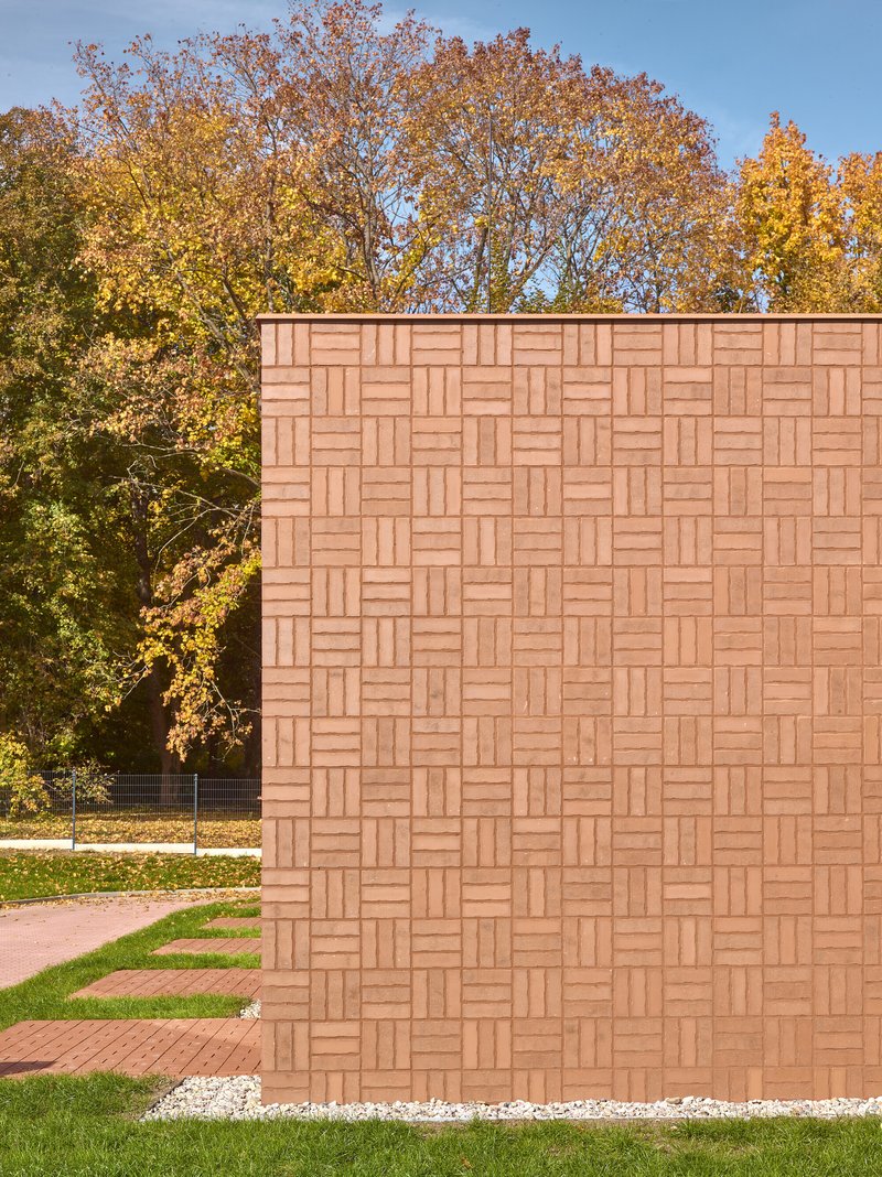 Basketweave pattern red tile wall next to autumn trees with yellow and orange foliage