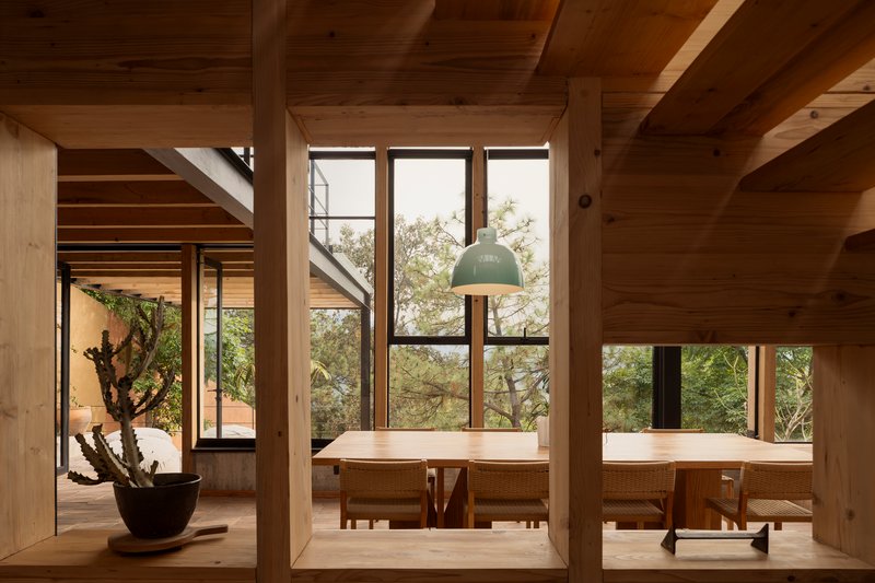 Dining nook with built-in timber benches under tall windows framed by exposed wood columns and beams