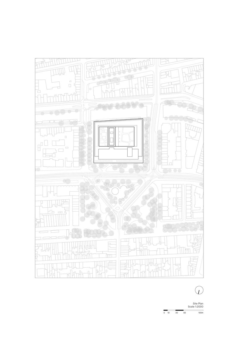 Site plan drawing showing a rectangular building within surrounding urban fabric and tree rows