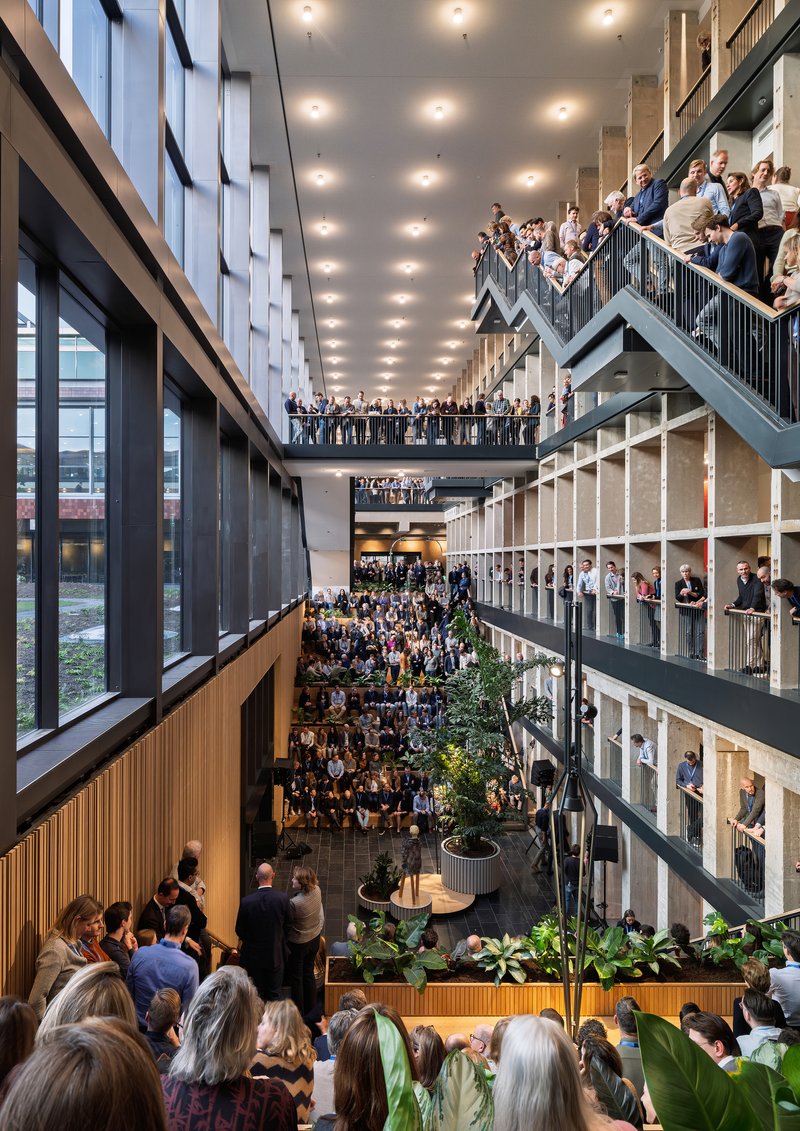 Multi-story atrium packed with people on balconies and stairs around planted greenery at ground level