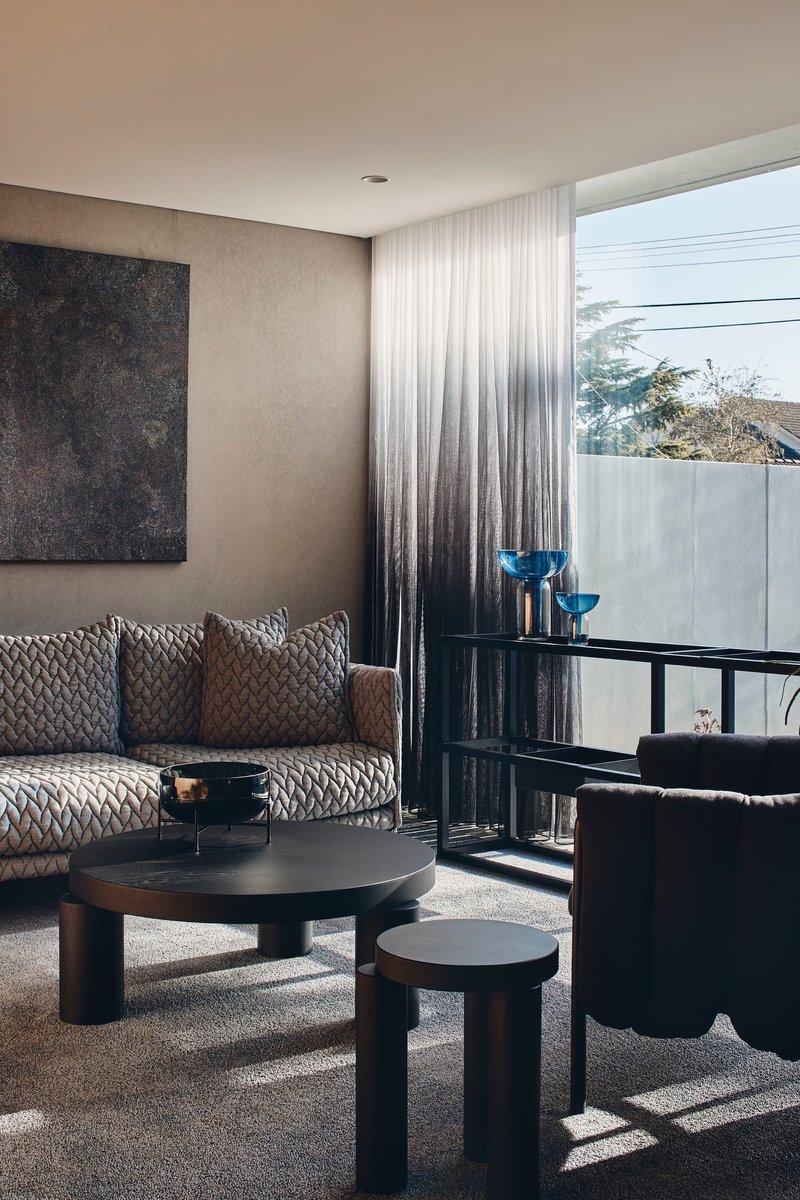 Living room with gradient curtains and floor-to-ceiling window overlooking trees and concrete wall