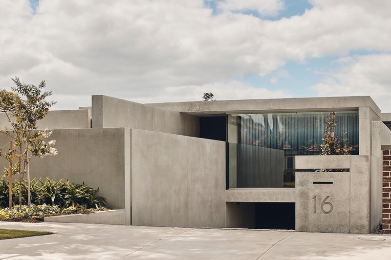 Recessed entry portal in the concrete facade with horizontal glazing and a cast address number